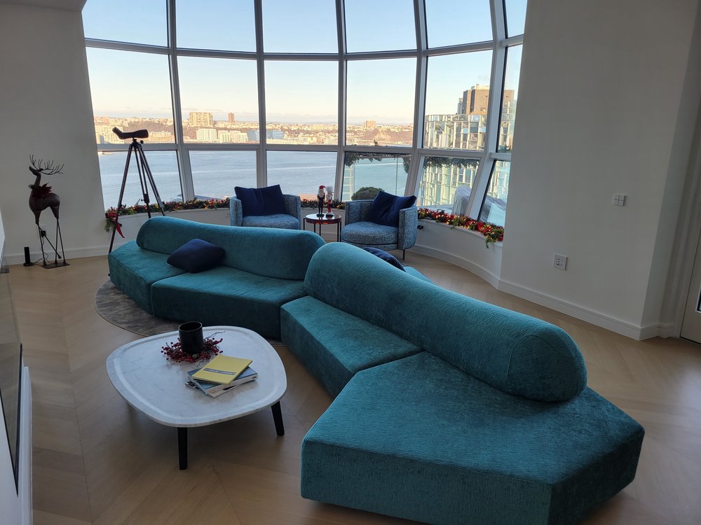 Contemporary high-rise penthouse living room showcasing a sculptural curved modular sofa in teal upholstery