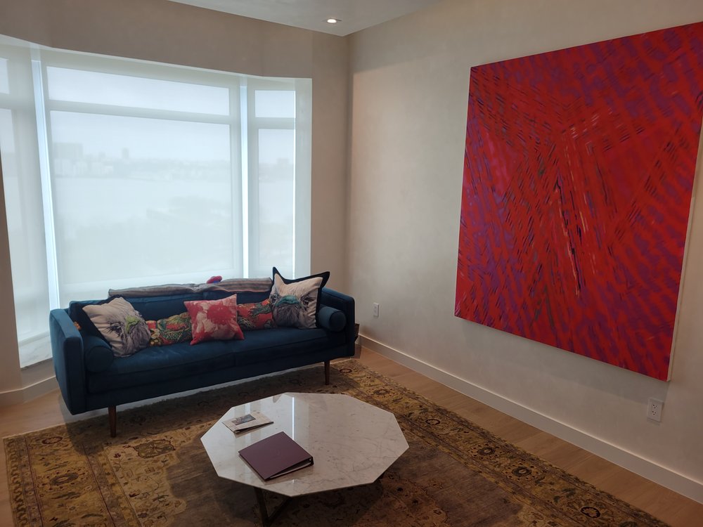 Contemporary bedroom or media lounge with wall of large windows featuring motorized shade treatment providing