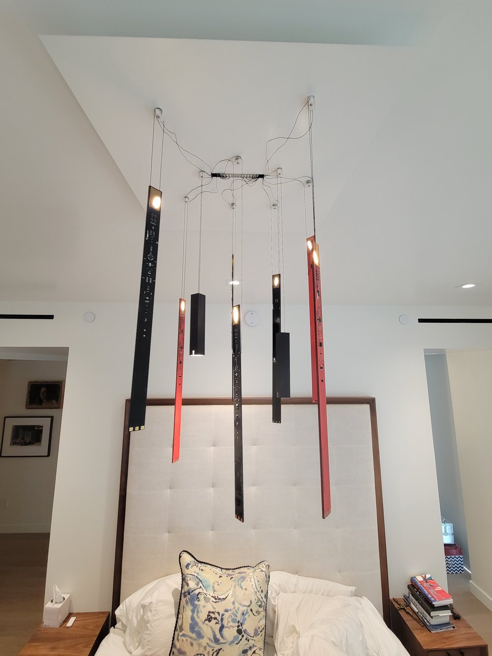 Contemporary bedroom featuring a striking mobile-style pendant light fixture with multiple hanging elements