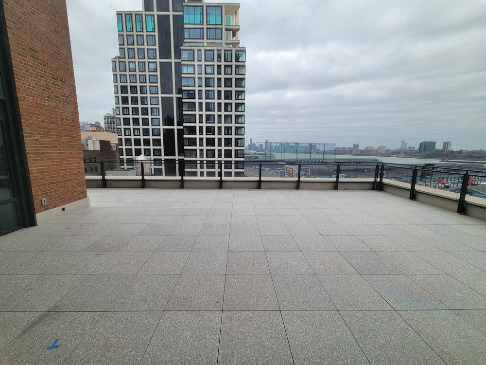 Rooftop terrace in urban setting with expansive city skyline views. Clean-lined glass and metal safety