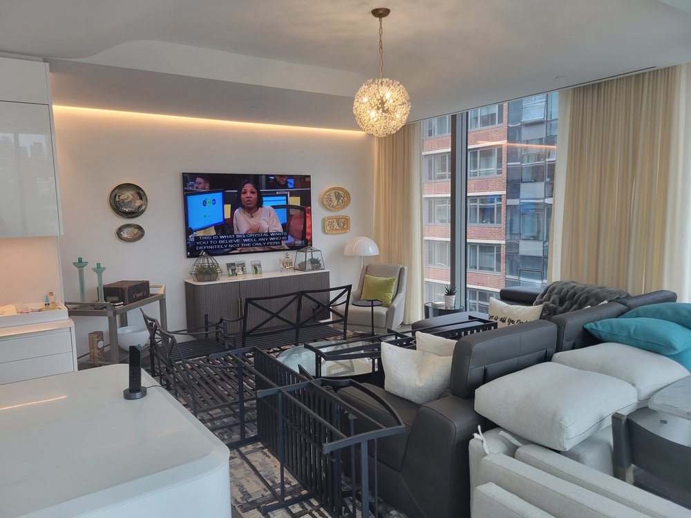 Living room portion of the high-rise apartment featuring a gray sectional with colorful accent pillows