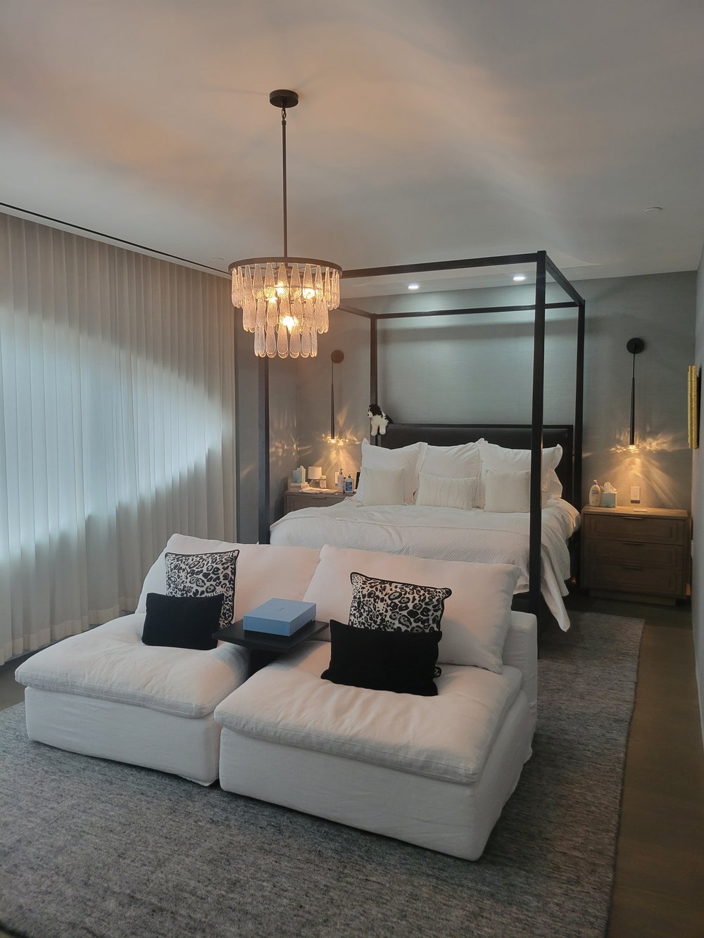 Luxury hotel or residential bedroom featuring a black-metal canopy bed with white linens and decorative black