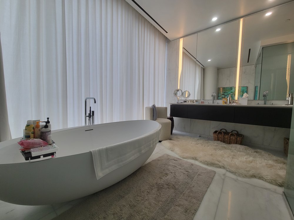 Luxury primary bathroom photographed from opposite end showing the elegant white soaking tub and spa