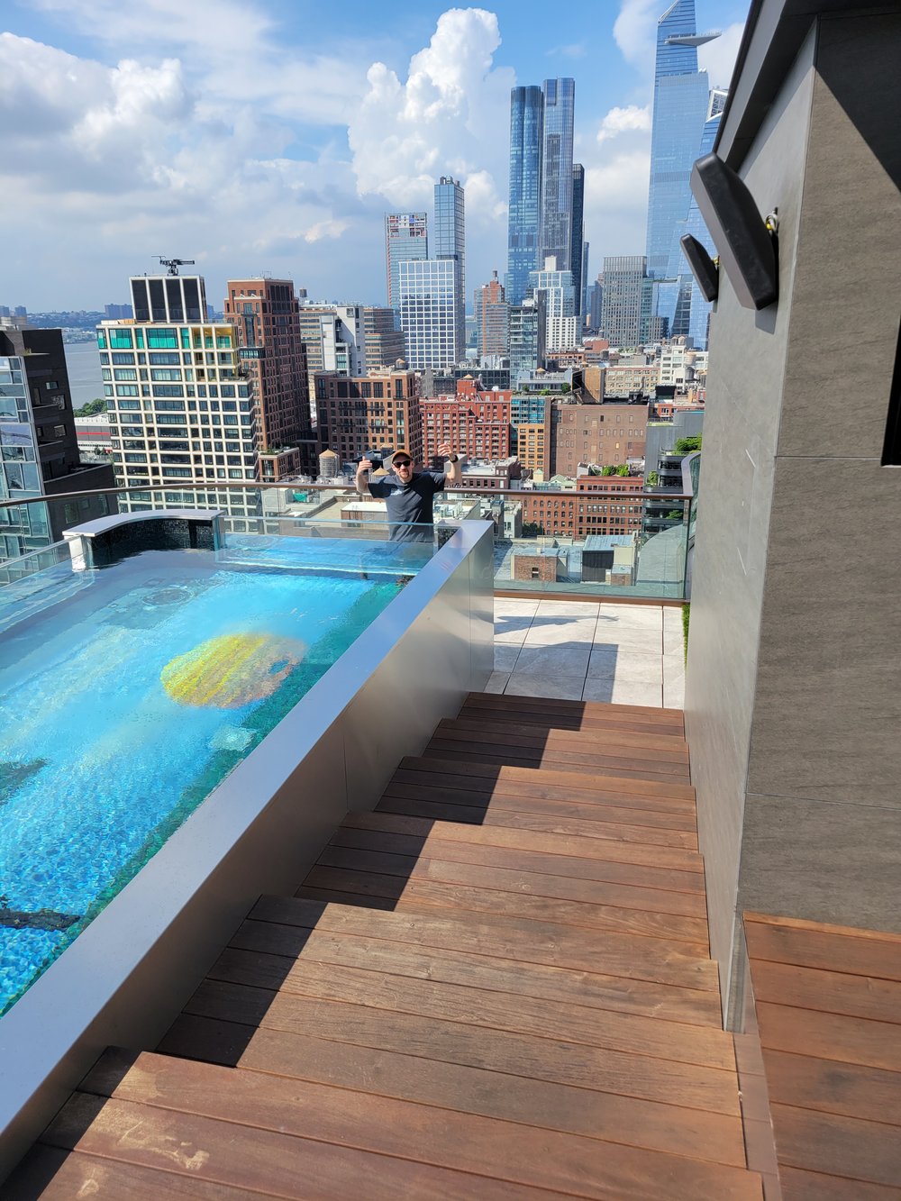 A spectacular rooftop infinity-edge pool installation overlooking Manhattan's iconic skyline, featuring a