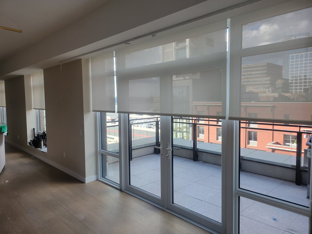 An open rooftop terrace space with professional motorized roller shade installation across extensive
