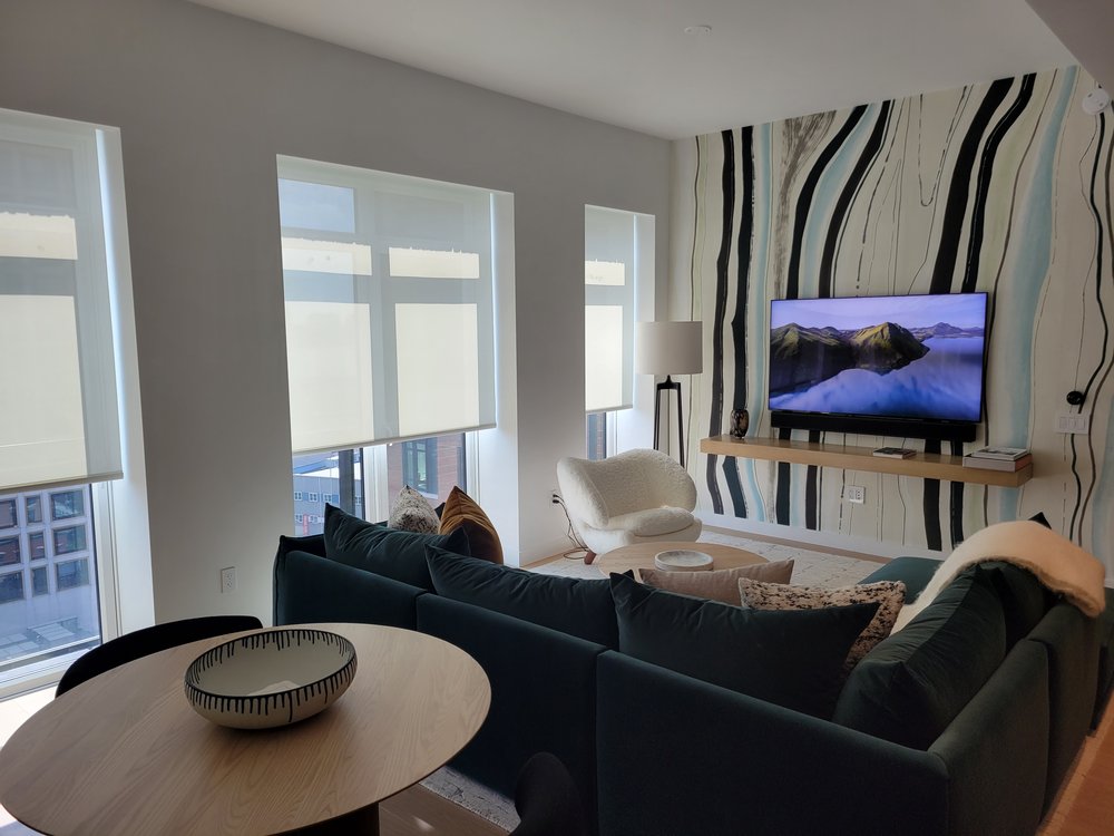 Contemporary high-rise living room with striped geometric accent wall in blue, black and white. Black fabric