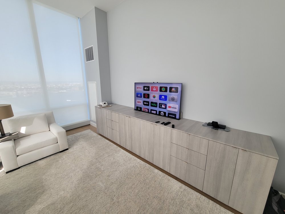 Minimalist media room in a high-rise apartment with expansive window views over water and cityscape. A