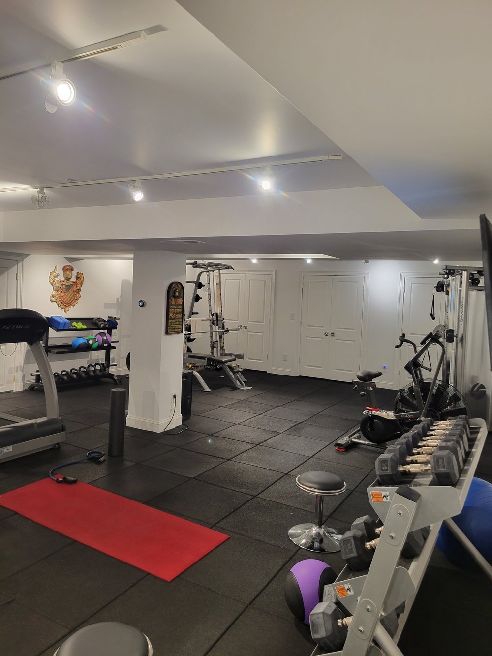 A finished residential gym with modern architectural details featuring white coffered ceiling and recessed