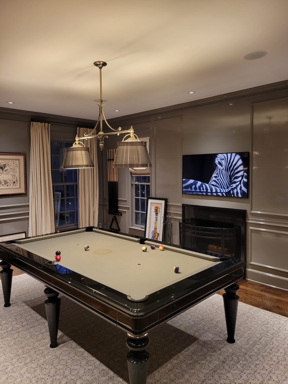 A sophisticated media room featuring a full-size billiards table as the centerpiece under an elegant
