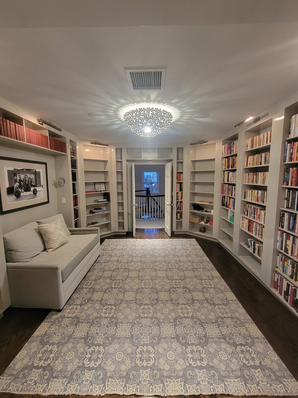 Sophisticated library or office lounge with floor-to-ceiling built-in white shelving on both walls filled