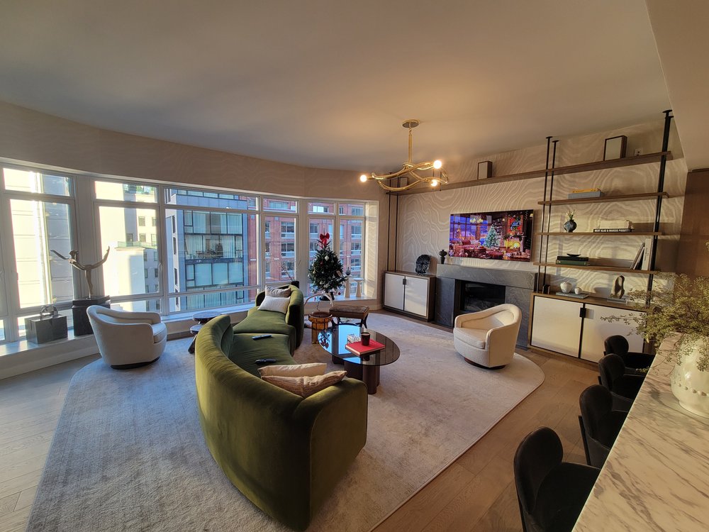 High-end modern living room with floor-to-ceiling windows offering expansive city views, featuring a curved