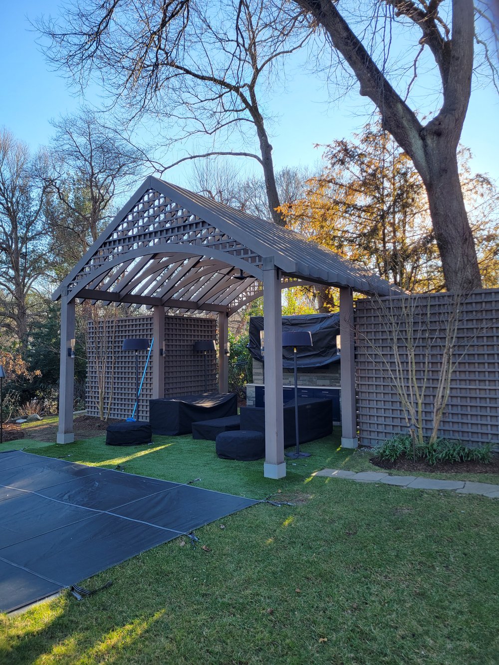 Outdoor patio structure featuring contemporary pergola design with white columns and black lattice overhead