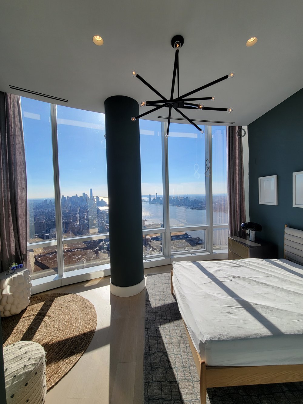 A modern bedroom in a high-rise apartment featuring a contemporary black star-shaped pendant light fixture