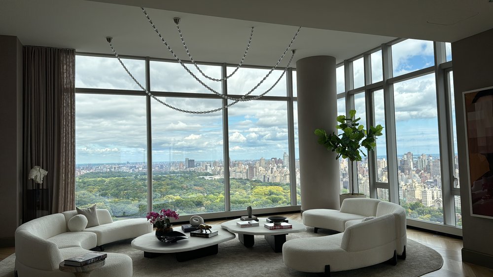 Luxury high-rise living room featuring custom curved modular seating in cream upholstery, sculptural coffee