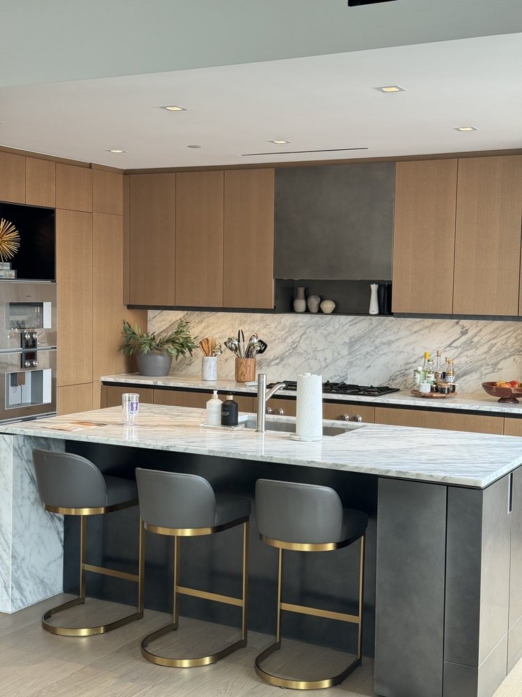 Upscale dining and entertaining area with three sculptural dining chairs featuring gray upholstery and