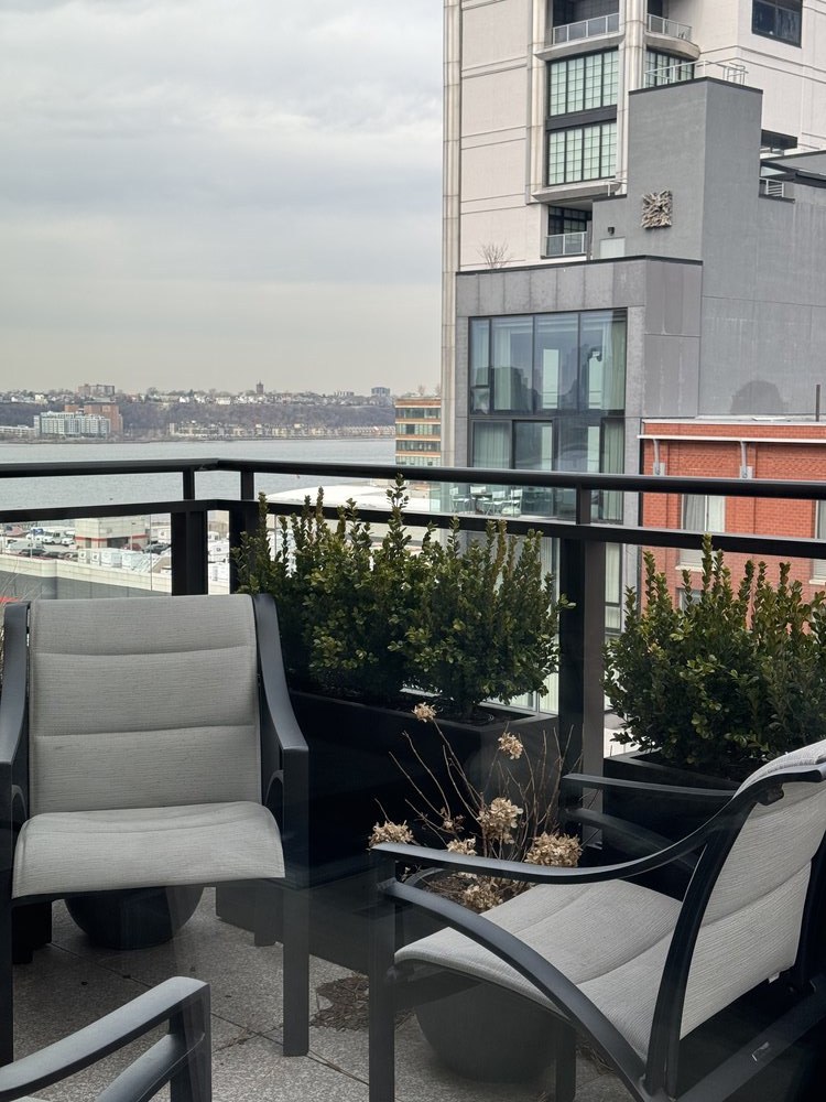 High-rise terrace and entertainment space featuring modern outdoor seating with white cushioned lounge chairs