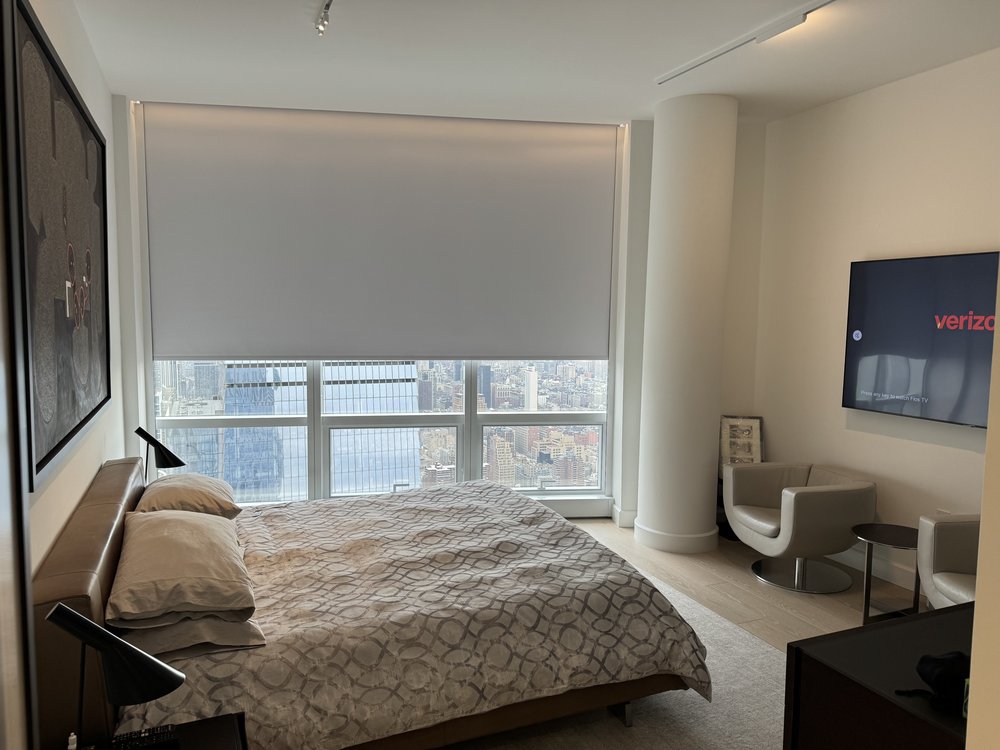 Luxury master bedroom in a high-rise setting featuring a contemporary bed with patterned bedding, large