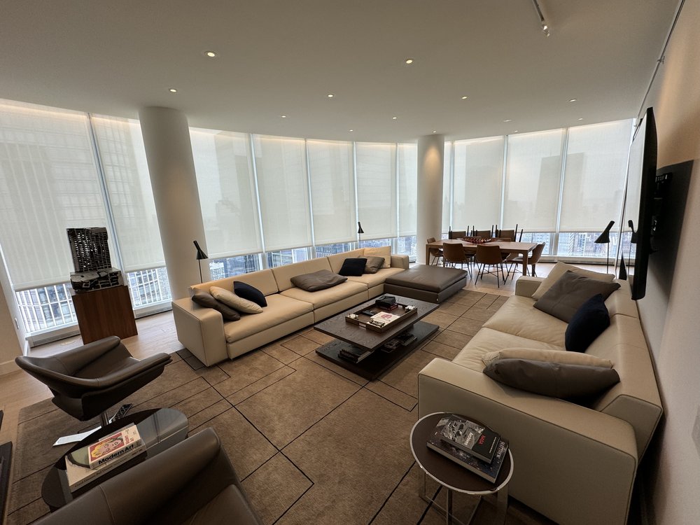 Expansive luxury living room and entertainment space featuring a curved motorized roller shade system across