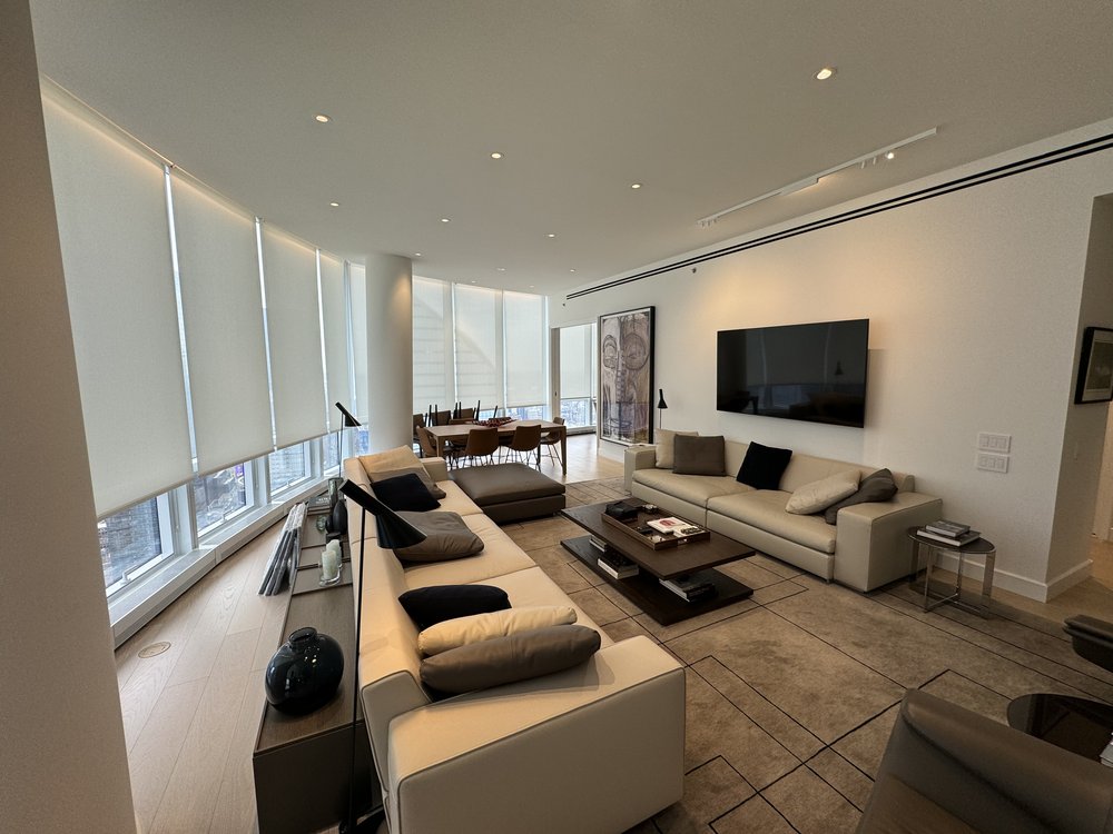 Contemporary living room showcasing motorized roller shades integrated across expansive windows, offering