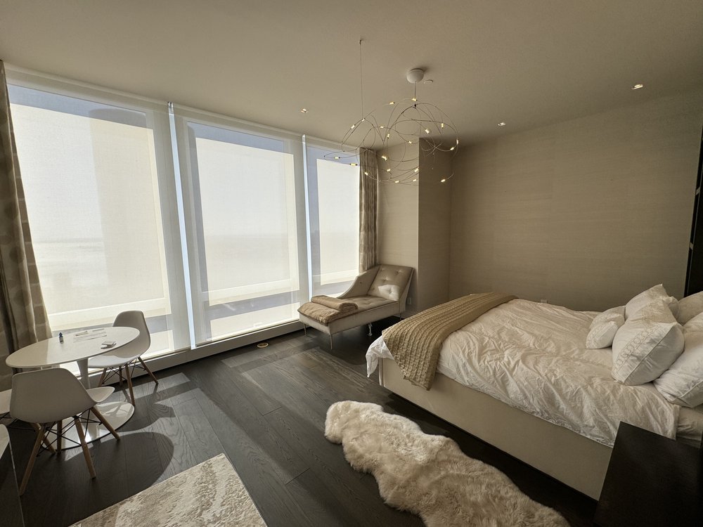 Luxurious high-rise bedroom with floor-to-ceiling windows showcasing panoramic Manhattan views. The space