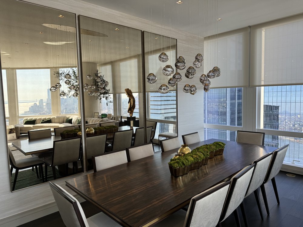 Stunning high-rise dining and living space with floor-to-ceiling windows framing Manhattan's urban landscape.