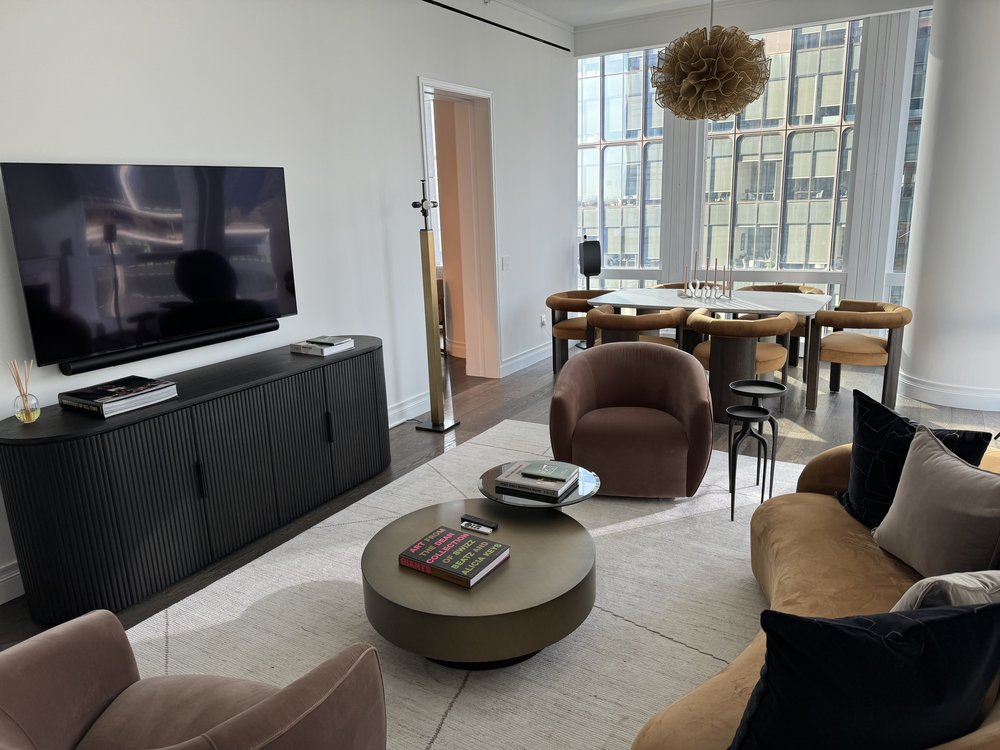 Sophisticated open-plan living and dining space in a high-rise residence. The living area features warm brown