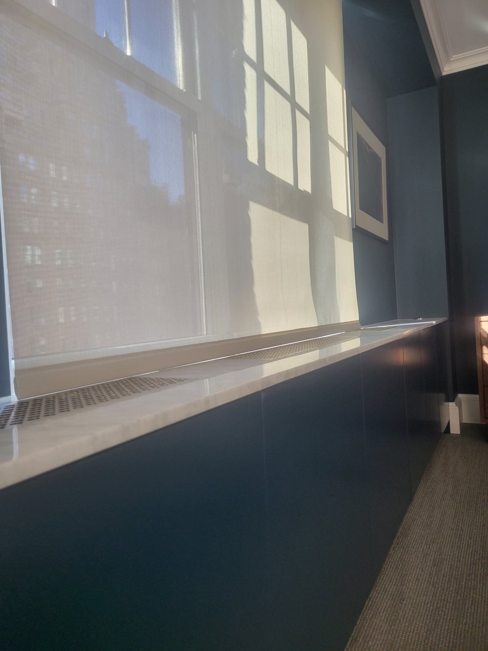 Motorized window treatment system installed on expansive windows overlooking a high-rise cityscape with water