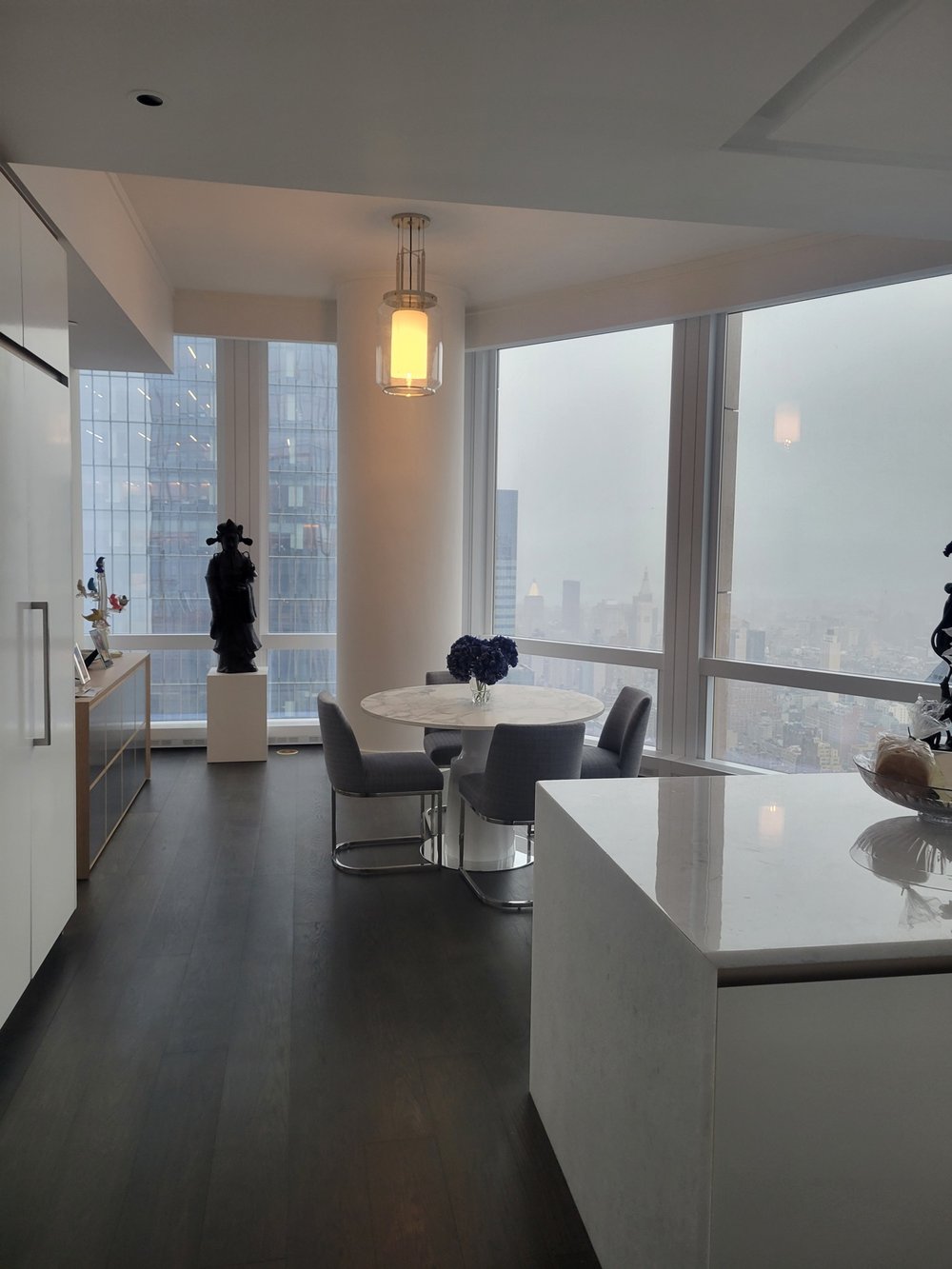 Modern minimalist kitchen and dining room with panoramic floor-to-ceiling windows framing a dramatic