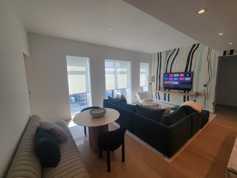 Luxurious high-rise living room with panoramic windows delivering commanding city views. Striped geometric
