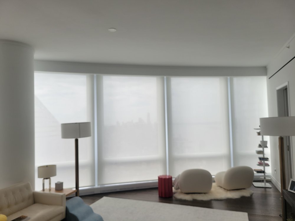 Minimalist bedroom with sophisticated window treatments creating diffused, ambient light. Two contemporary