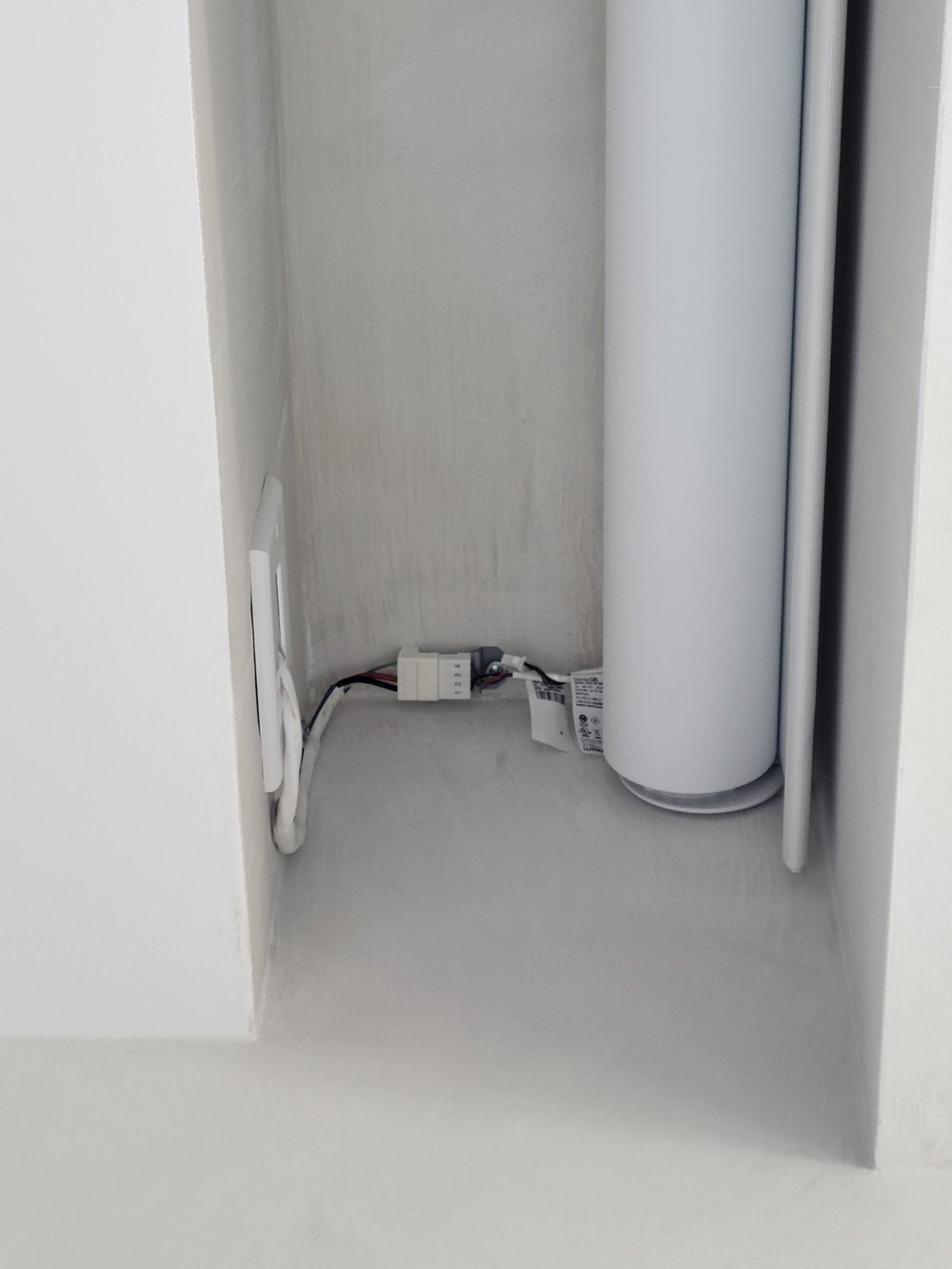 Technical closeup of motorized shade motor and mechanical assembly installed in a tight wall cavity. Shows