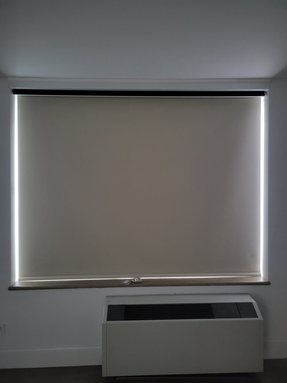 Duplicate/near-identical shot of motorized roller shades with integrated LED backlighting. Same window