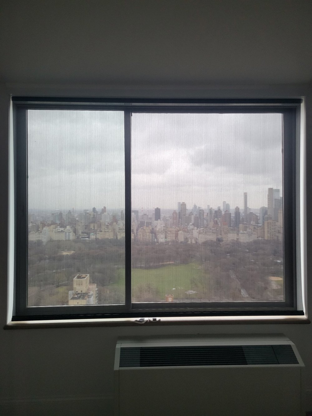 Premium high-rise window installation showcasing an integrated motorized shade system with dual layers. Dark