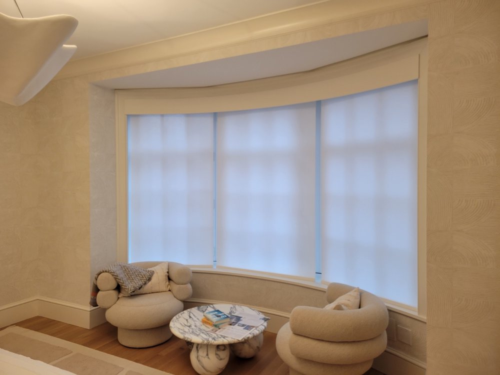 Modern finished bedroom with integrated window seating and luxury furnishings. A curved window nook seat
