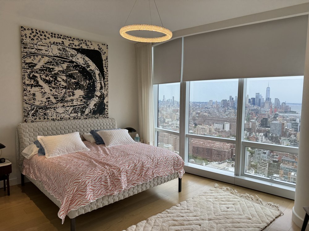 Luxury high-rise bedroom in Manhattan featuring floor-to-ceiling windows with expansive city skyline views.