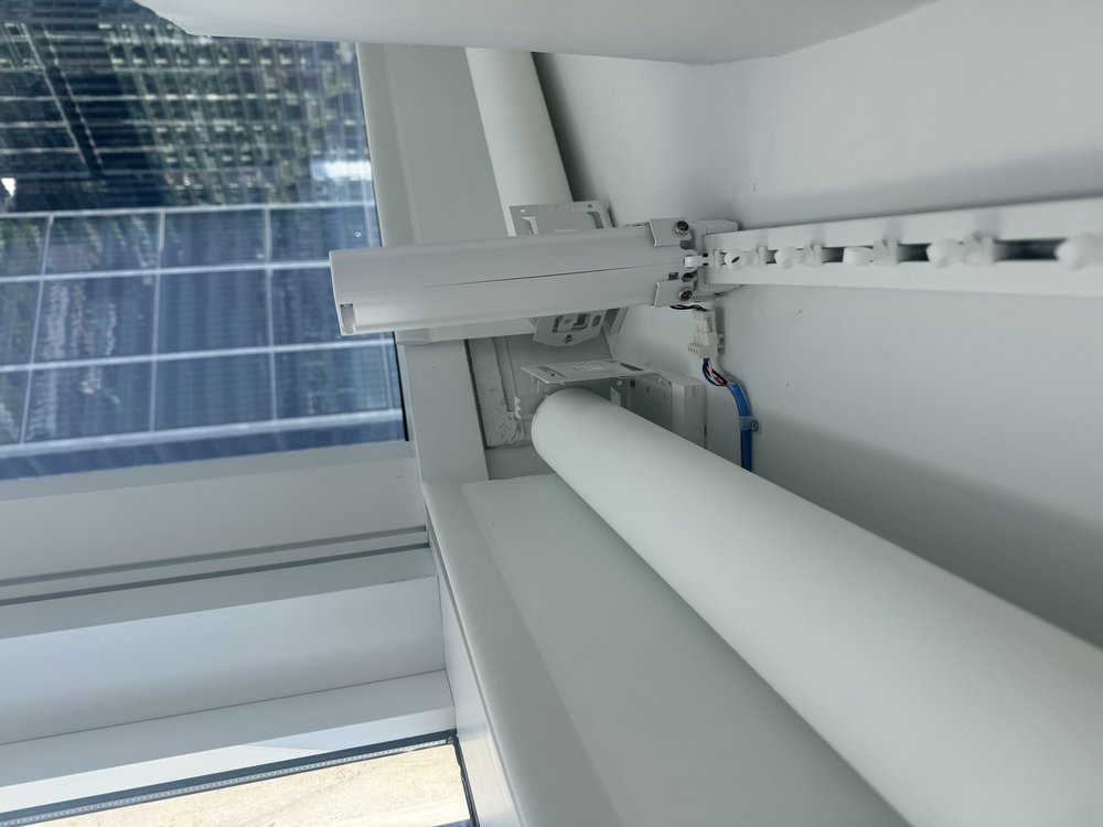 Close-up detail of motorized roller shade mechanism and installation. The image captures the track system,