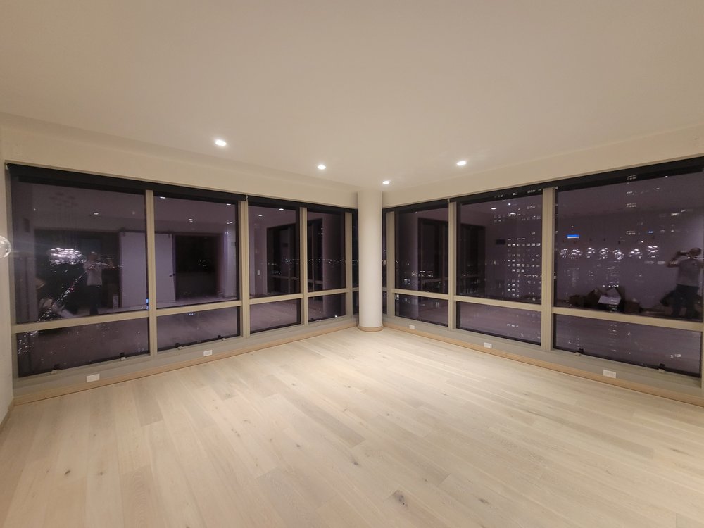 Expansive finished living space on a high floor with floor-to-ceiling multi-panel windows framing a nighttime