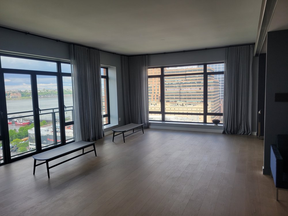 High-rise residential living space with expansive corner windows providing unobstructed views of Manhattan