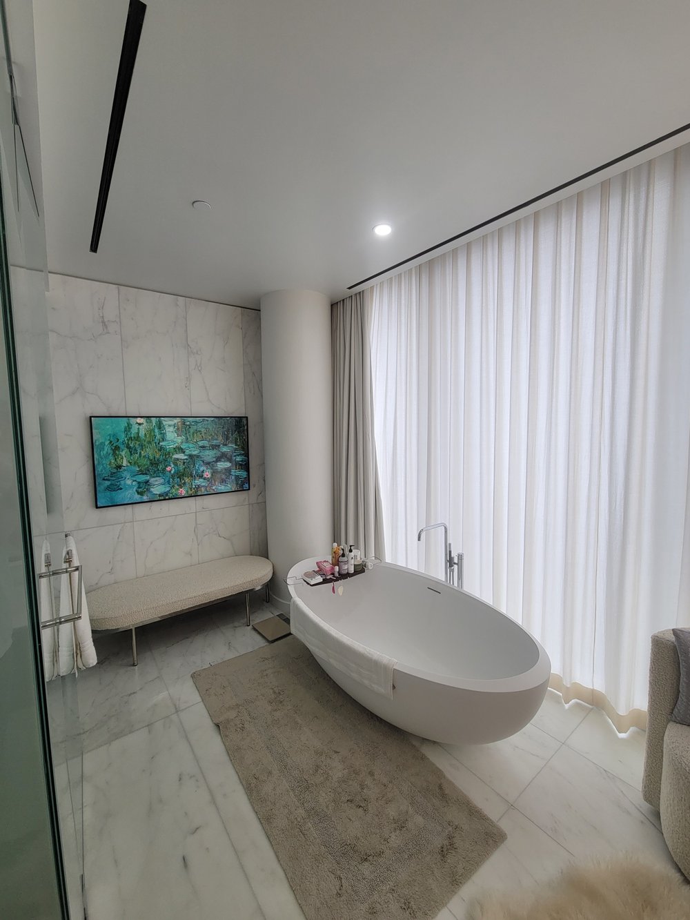 Luxury master bathroom featuring a sculptural white freestanding oval soaking tub positioned as the focal