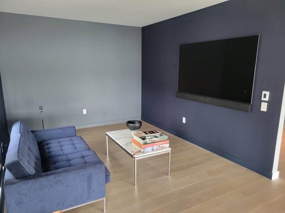 Minimalist bedroom with blue pendant light fixtures suspended above white upholstered bed with gray