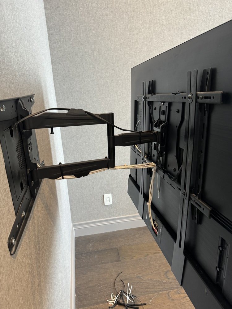 Wall-mounted TV articulating bracket installation showcasing a full-motion mount system with visible cable