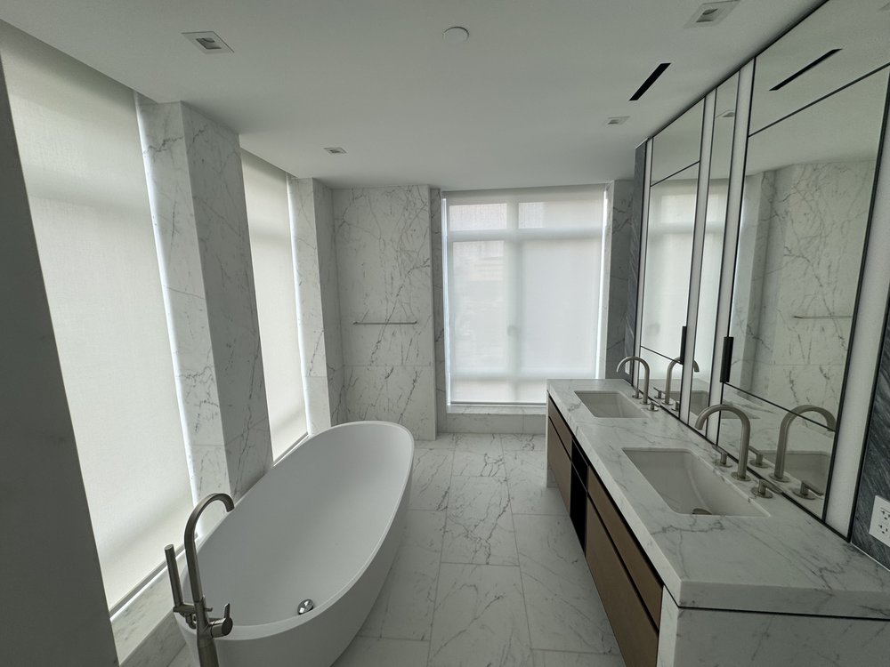 Luxury master bathroom finished in high-end materials. Floor-to-ceiling white and gray marble cladding