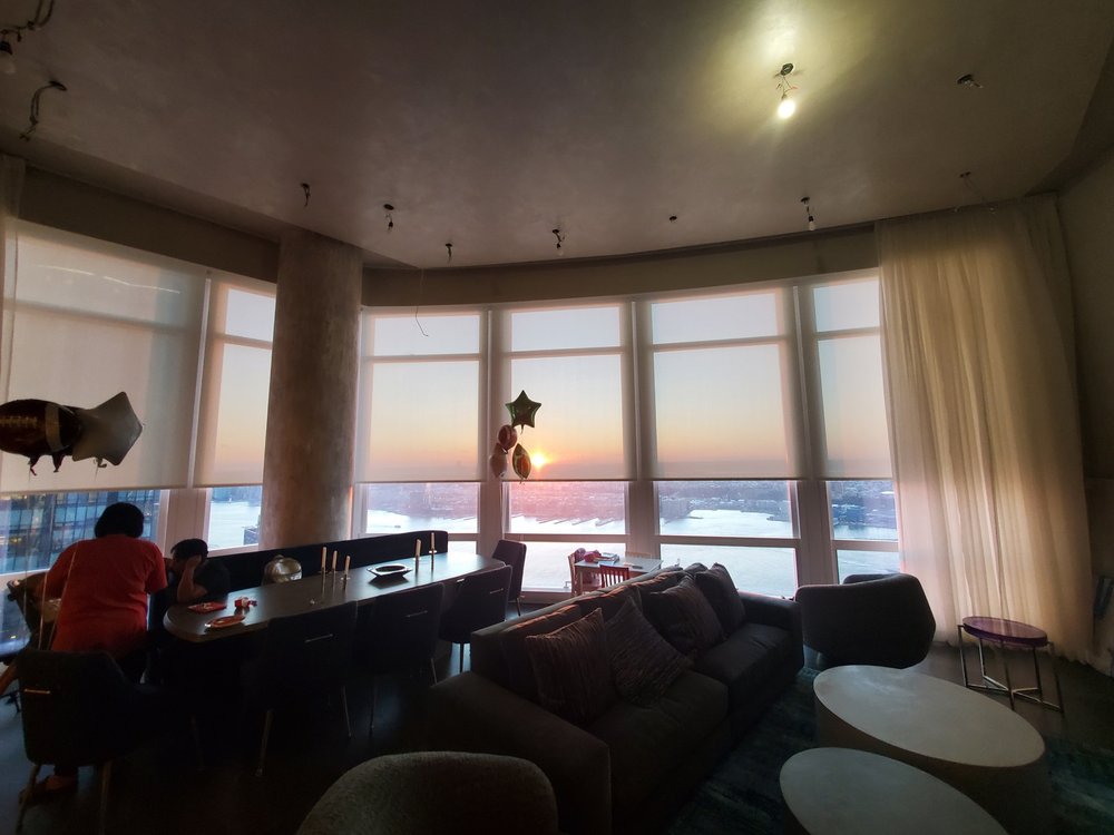 Spectacular high-rise living room and bar area with panoramic floor-to-ceiling windows showcasing nighttime