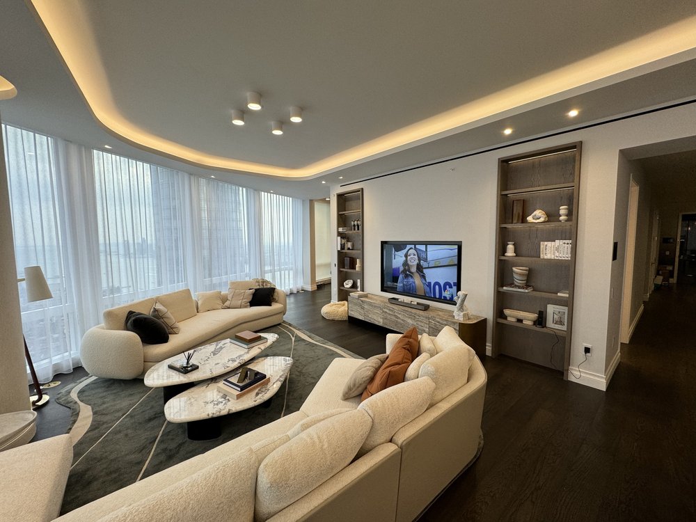 Luxurious contemporary living room featuring curved cream-colored sectional sofas arranged around a media