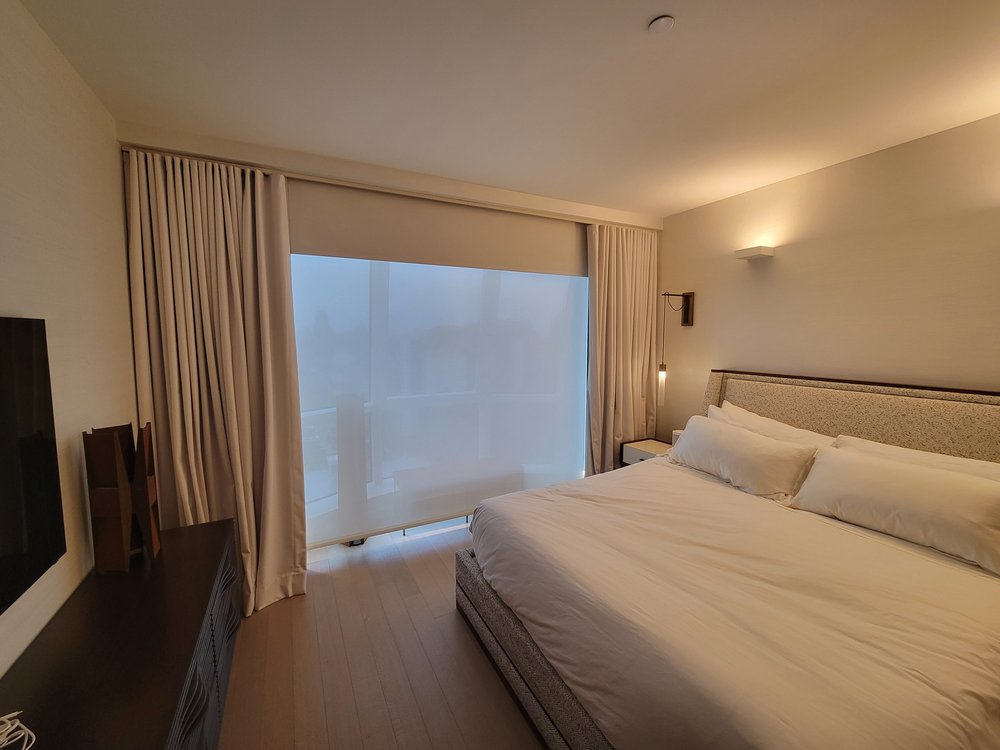 Finished bedroom featuring a dramatic motorized blackout shade installation covering floor-to-ceiling