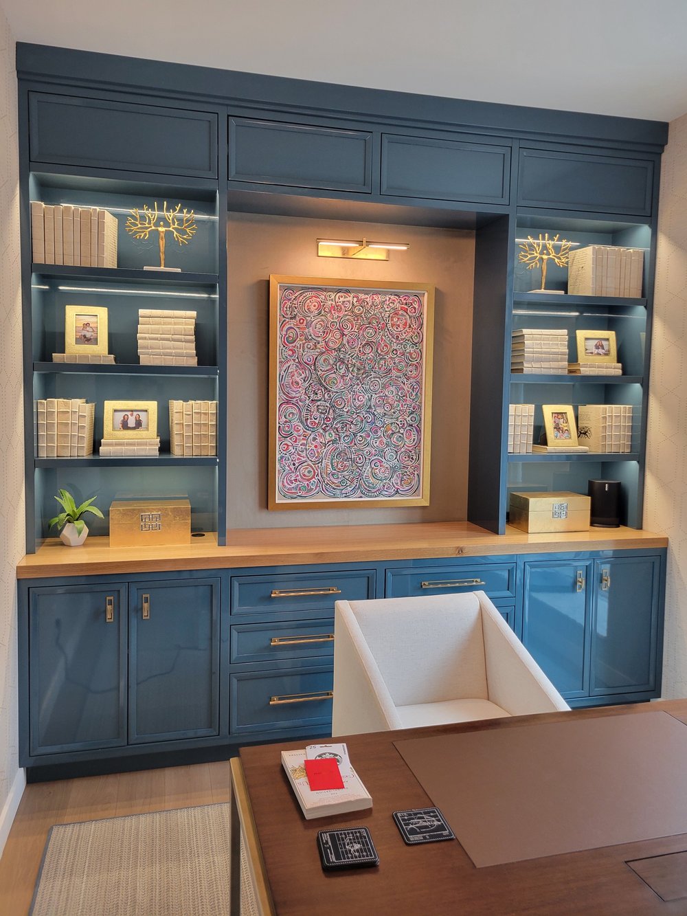 Luxury built-in wall cabinetry system with dark blue painted finishes and integrated warm accent lighting.