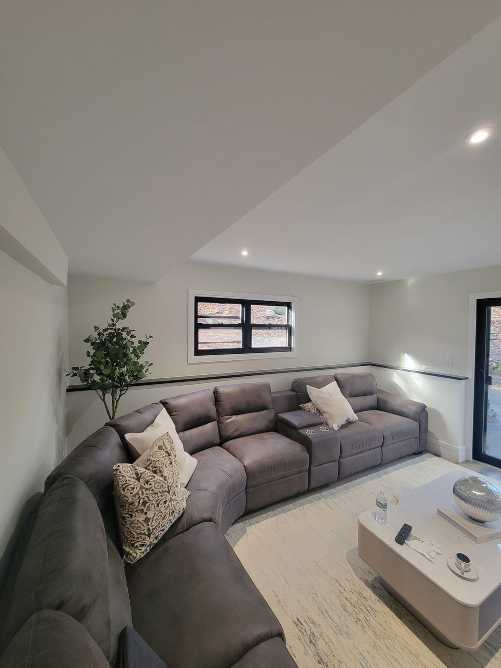Dedicated media room with custom-built gray leather sectional reclining sofa. Angled architectural ceiling