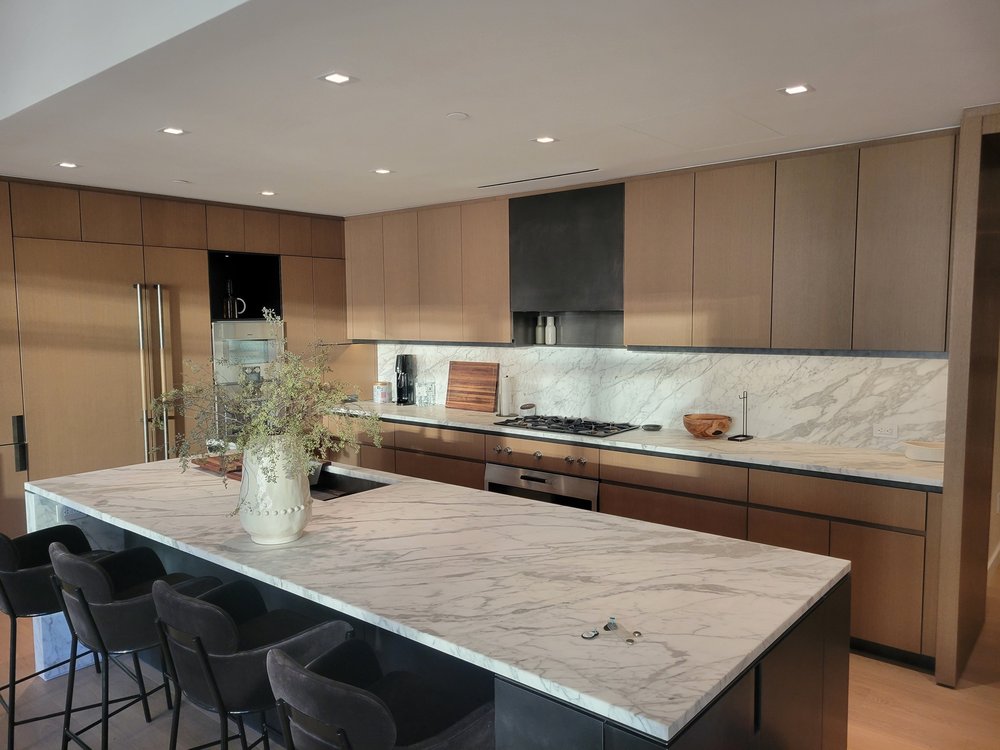 Contemporary kitchen with premium finishes featuring warm natural wood cabinetry in honey tones, white