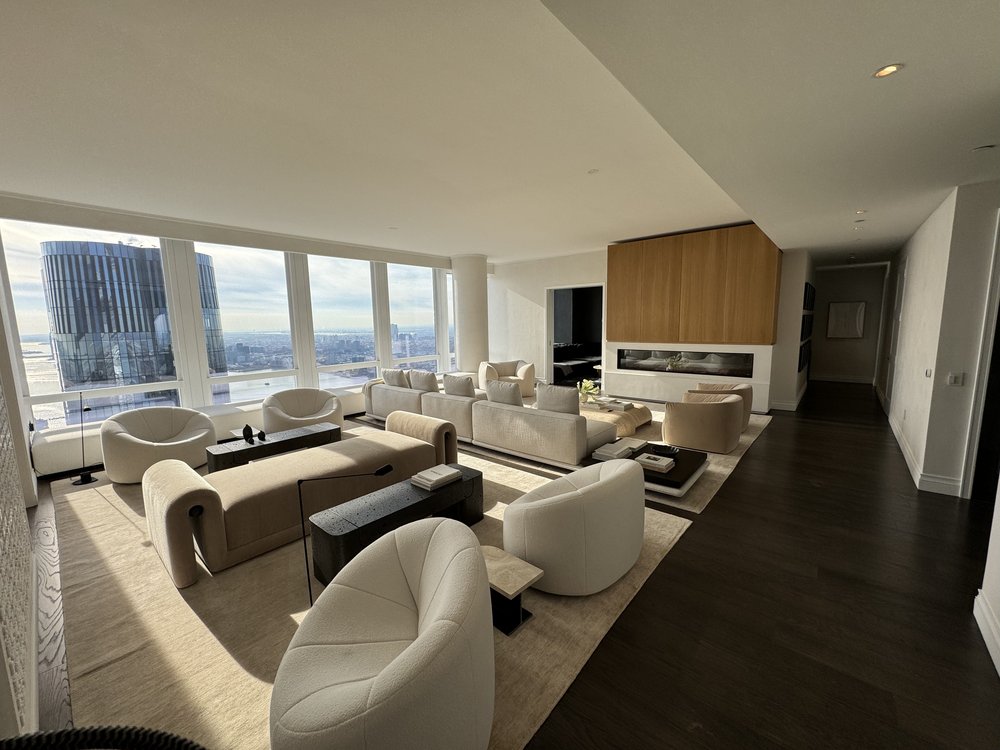 Luxury high-rise living room in a modern residential tower with expansive floor-to-ceiling windows framing