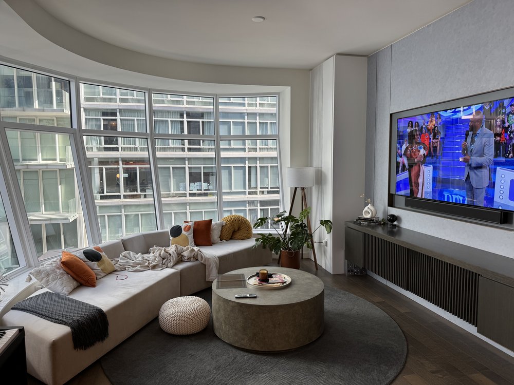 Modern living room or showroom space with gray upholstered sectional sofa, integrated glass partition wall